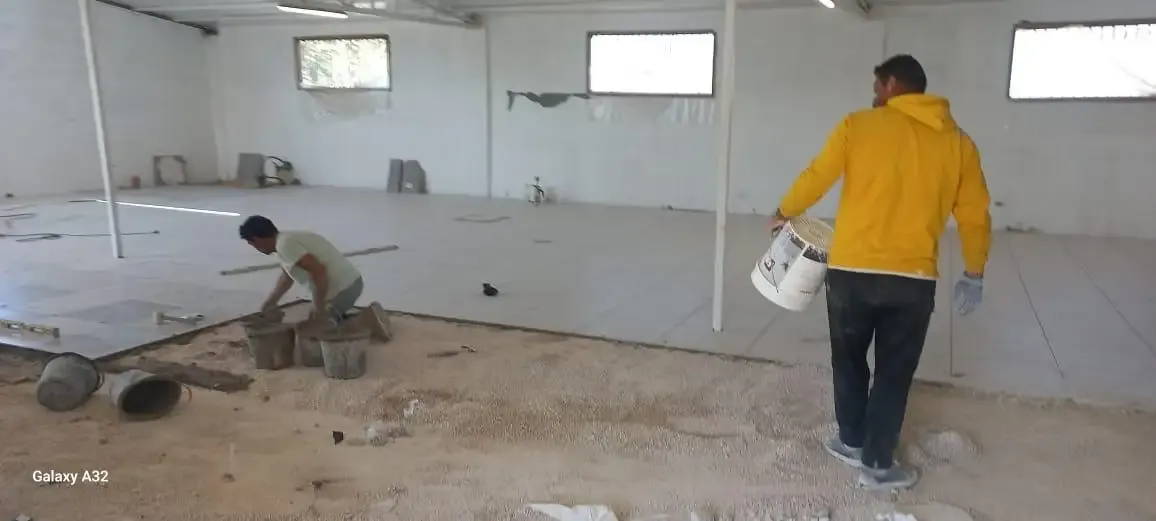 Workers laying floor tiles inside the food processing factory